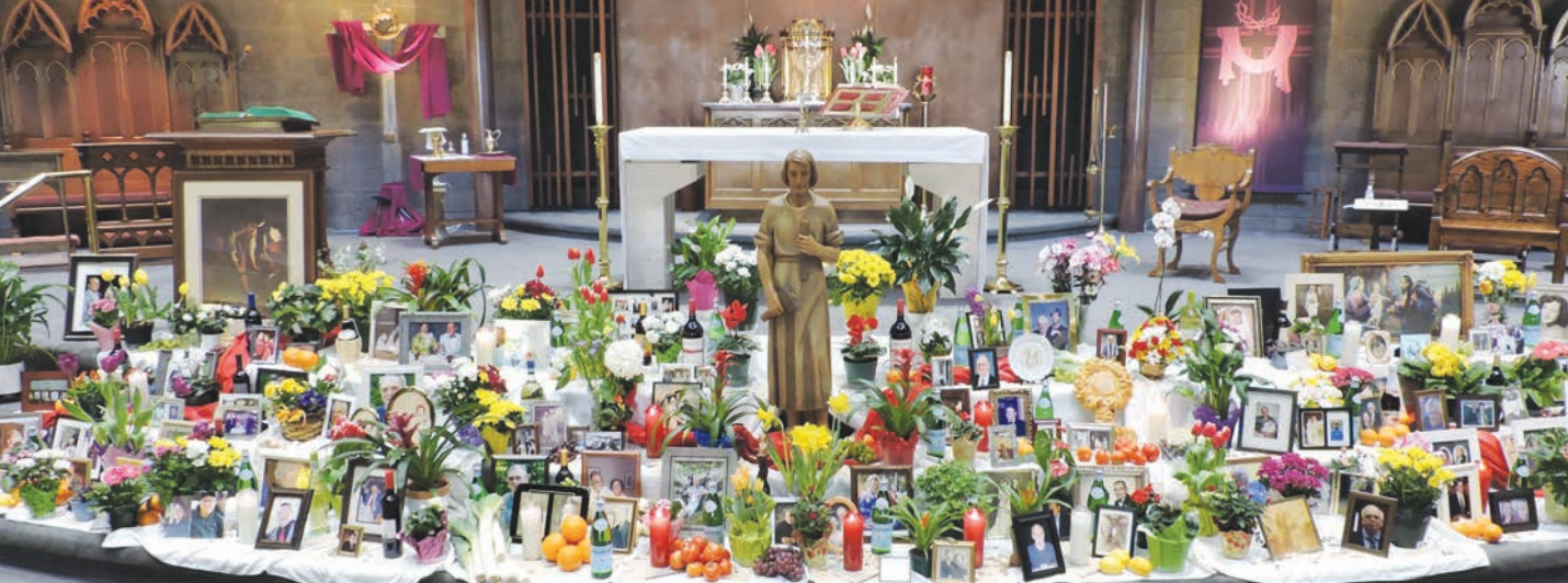 The altar at St. Martin, with a statue of St. Joseph and photos and flowers